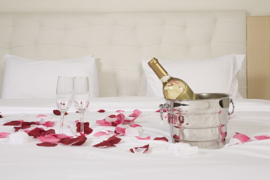 butelka szampana i kieliszki na łóżku