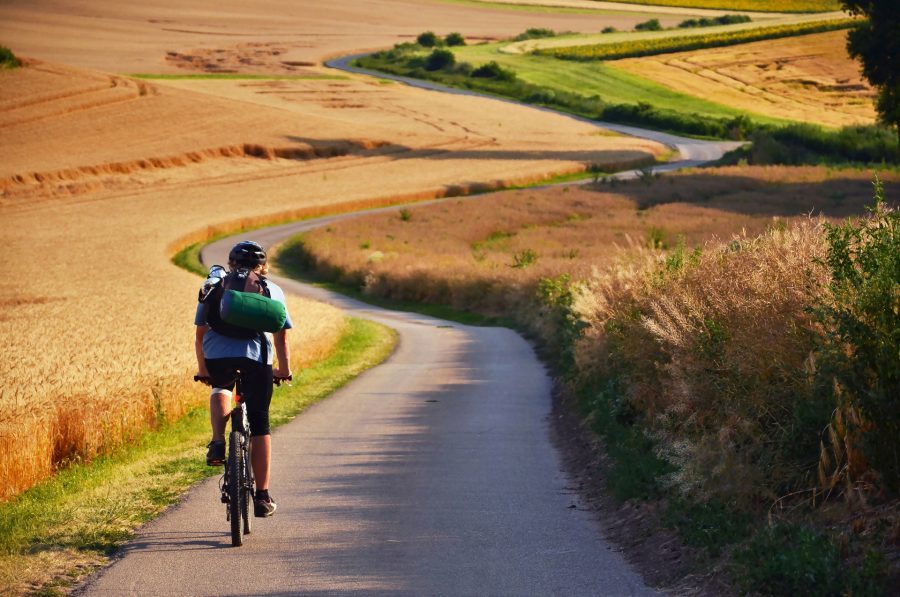 rowerzysta jadący polami wie jak się spakować na wakacje w Polsce